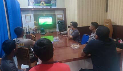 Kapolsek Buay Madang Timur Iptu Swisspo, bersama personel dan warga pencinta sepak bola saat menyaksikan pertandingan Pesta Bola Dunia 2026 antara Swiss vs Bosnia di ruang pertemuan Mako Polsek Buay Madang Timur, OKU Timur.