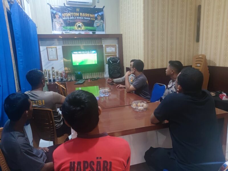 Kapolsek Buay Madang Timur Iptu Swisspo, bersama personel dan warga pencinta sepak bola saat menyaksikan pertandingan Pesta Bola Dunia 2026 antara Swiss vs Bosnia di ruang pertemuan Mako Polsek Buay Madang Timur, OKU Timur. 