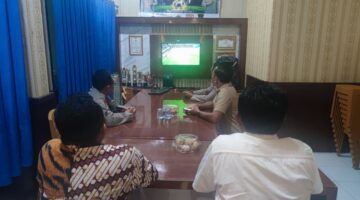 Kapolsek Buay Madang Timur Iptu Swisspo, bersama personel dan warga setempat menyaksikan pertandingan laga Pesta Bola Dunia 2026 antara Amerika Serikat melawan Australia di Mako Polsek Buay Madang Timur, Kabupaten OKU Timur.