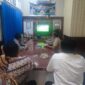 Kapolsek Buay Madang Timur Iptu Swisspo, bersama personel dan warga setempat menyaksikan pertandingan laga Pesta Bola Dunia 2026 antara Amerika Serikat melawan Australia di Mako Polsek Buay Madang Timur, Kabupaten OKU Timur. 