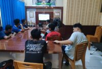 Jajaran anggota Polsek Buay Madang Timur bersama warga pencinta sepak bola saat menyaksikan pertandingan laga Pesta Bola Dunia 2026 antara Belgia vs Iran di Mako Polsek Buay Madang Timur, OKU Timur. 