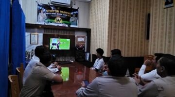 Kapolsek Buay Madang Timur IPTU Swisspo, bersama jajaran personel dan warga pencinta sepak bola menyaksikan pertandingan Portugal vs Uzbekistan saat acara Nonton Bareng (Nobar) Pesta Bola Dunia 2026 di Mako Polsek Buay Madang Timur, Kabupaten OKU Timur.