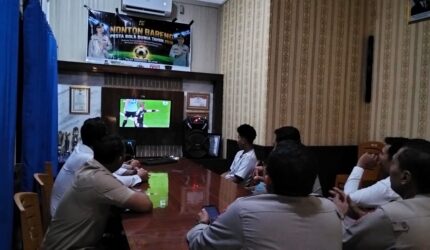 Kapolsek Buay Madang Timur IPTU Swisspo, bersama jajaran personel dan warga pencinta sepak bola menyaksikan pertandingan Portugal vs Uzbekistan saat acara Nonton Bareng (Nobar) Pesta Bola Dunia 2026 di Mako Polsek Buay Madang Timur, Kabupaten OKU Timur.