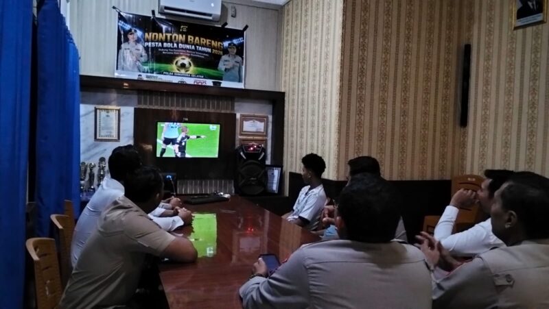 Kapolsek Buay Madang Timur IPTU Swisspo, bersama jajaran personel dan warga pencinta sepak bola menyaksikan pertandingan Portugal vs Uzbekistan saat acara Nonton Bareng (Nobar) Pesta Bola Dunia 2026 di Mako Polsek Buay Madang Timur, Kabupaten OKU Timur. 
