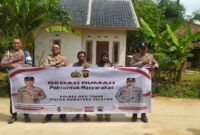 Kapolsek Buay Madang Timur Iptu Swisspo, bersama jajaran personel, perangkat desa, serta warga penerima manfaat, Nurmala Sari, membentangkan spanduk di depan rumah yang telah selesai dibedah di Desa Tugu Harum, Kecamatan Belitang Madang Raya, Kabupaten OKU Timur, Sumatera Selatan. 