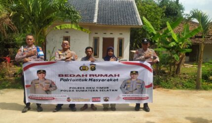 Kapolsek Buay Madang Timur Iptu Swisspo, bersama jajaran personel, perangkat desa, serta warga penerima manfaat, Nurmala Sari, membentangkan spanduk di depan rumah yang telah selesai dibedah di Desa Tugu Harum, Kecamatan Belitang Madang Raya, Kabupaten OKU Timur, Sumatera Selatan.