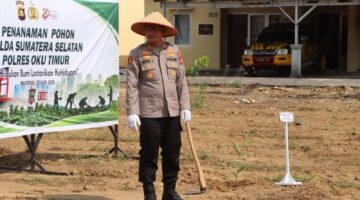 Kapolres OKU Timur AKBP Adik Listiyono, berdiri di samping spanduk bertuliskan 