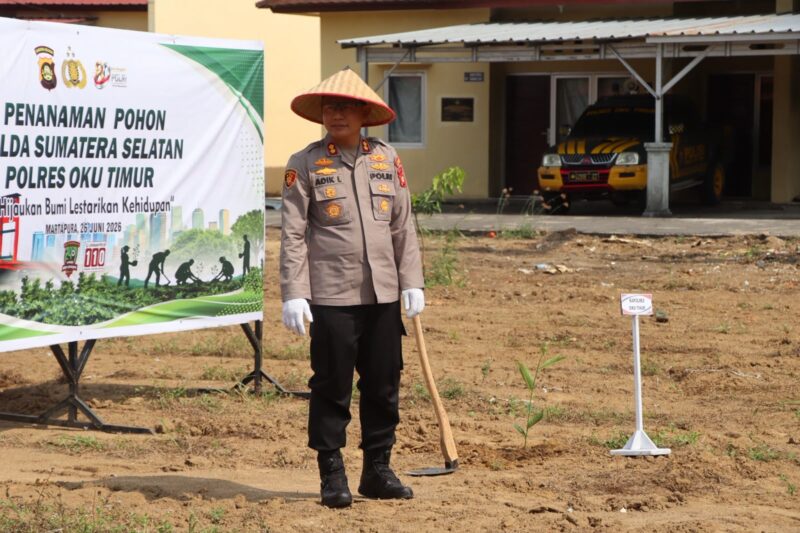 Kapolres OKU Timur AKBP Adik Listiyono, berdiri di samping spanduk bertuliskan 