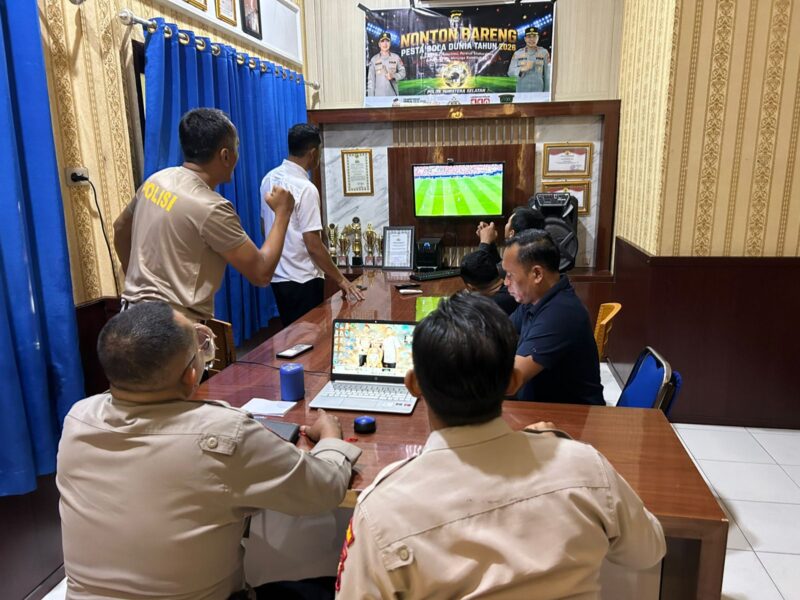 Jajaran personel Polsek Buay Madang Timur bersama masyarakat pencinta sepak bola menyaksikan pertandingan laga Norwegia melawan Perancis saat nonton bareng Pesta Bola Dunia 2026 di Mako Polsek Buay Madang Timur, OKU Timur. 