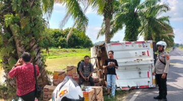 Anggota Polsek Buay Madang Timur berjaga di samping truk box Hino yang terguling di Jalan Raya Lintas Belitang BK 2, Desa Srikaton, Kecamatan Buay Madang Timur, OKU Timur. 