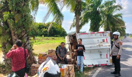 Anggota Polsek Buay Madang Timur berjaga di samping truk box Hino yang terguling di Jalan Raya Lintas Belitang BK 2, Desa Srikaton, Kecamatan Buay Madang Timur, OKU Timur.