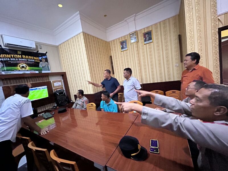 Kapolsek Buay Madang Timur IPTU Swisspo, bersama personel Polsek dan warga sekitar menyaksikan siaran langsung pertandingan Pesta Bola Dunia 2026 antara Spanyol vs Austria di Mako Polsek Buay Madang Timur, Kabupaten OKU Timur, Sumatra Selatan. 
