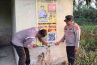 Kapolsek Buay Madang Timur, Iptu Swisspo, mendampingi anggotanya memasang spanduk sosialisasi layanan kepolisian dan larangan membakar hutan di Desa Teko Rejo, Kecamatan Buay Madang Timur, Kabupaten OKU Timur. 