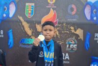 Atlet renang muda asal OKU Timur, Zakra Alkahfi Karim (Alfy), menunjukkan medali yang diraihnya pada Kejuaraan Renang Piala Kemenpora RI 2026 di Kolam Renang Pahoman, Bandar Lampung. 