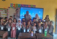 Personel Polsek Buay Madang Timur, Ps Kanit Binmas Bripka Ari Wicaksono dan Bhabinkamtibmas Bripka Nur Holik, berfoto bersama dewan guru dan siswa-siswi kelas 1 SDN 2 Rejodadi saat kegiatan penyuluhan tertib lalu lintas, anti-bullying, dan kedisiplinan di Desa Rejodadi, Kecamatan Buay Madang Timur. 