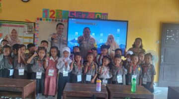 Personel Polsek Buay Madang Timur, Ps Kanit Binmas Bripka Ari Wicaksono dan Bhabinkamtibmas Bripka Nur Holik, berfoto bersama dewan guru dan siswa-siswi kelas 1 SDN 2 Rejodadi saat kegiatan penyuluhan tertib lalu lintas, anti-bullying, dan kedisiplinan di Desa Rejodadi, Kecamatan Buay Madang Timur.