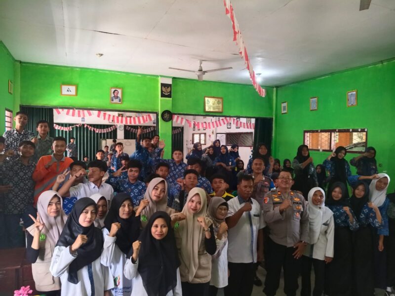 Kapolsek Buay Madang Timur IPTU Swisspo, (kanan depan, seragam dinas) berfoto bersama para guru, staf, dan siswa-siswi baru saat kegiatan MPLS/FORTASI di SMK Muhammadiyah 01 Rawabening, Desa Srikaton, OKU Timur. 