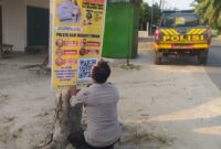 Personel Polsek Buay Madang Timur memasang banner Layanan Kepolisian 110 dan imbauan larangan karhutla di tepi jalan Desa Tanjung Mulya, Kecamatan Buay Madang Timur, OKU Timur. 