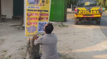 Personel Polsek Buay Madang Timur memasang banner Layanan Kepolisian 110 dan imbauan larangan karhutla di tepi jalan Desa Tanjung Mulya, Kecamatan Buay Madang Timur, OKU Timur. 