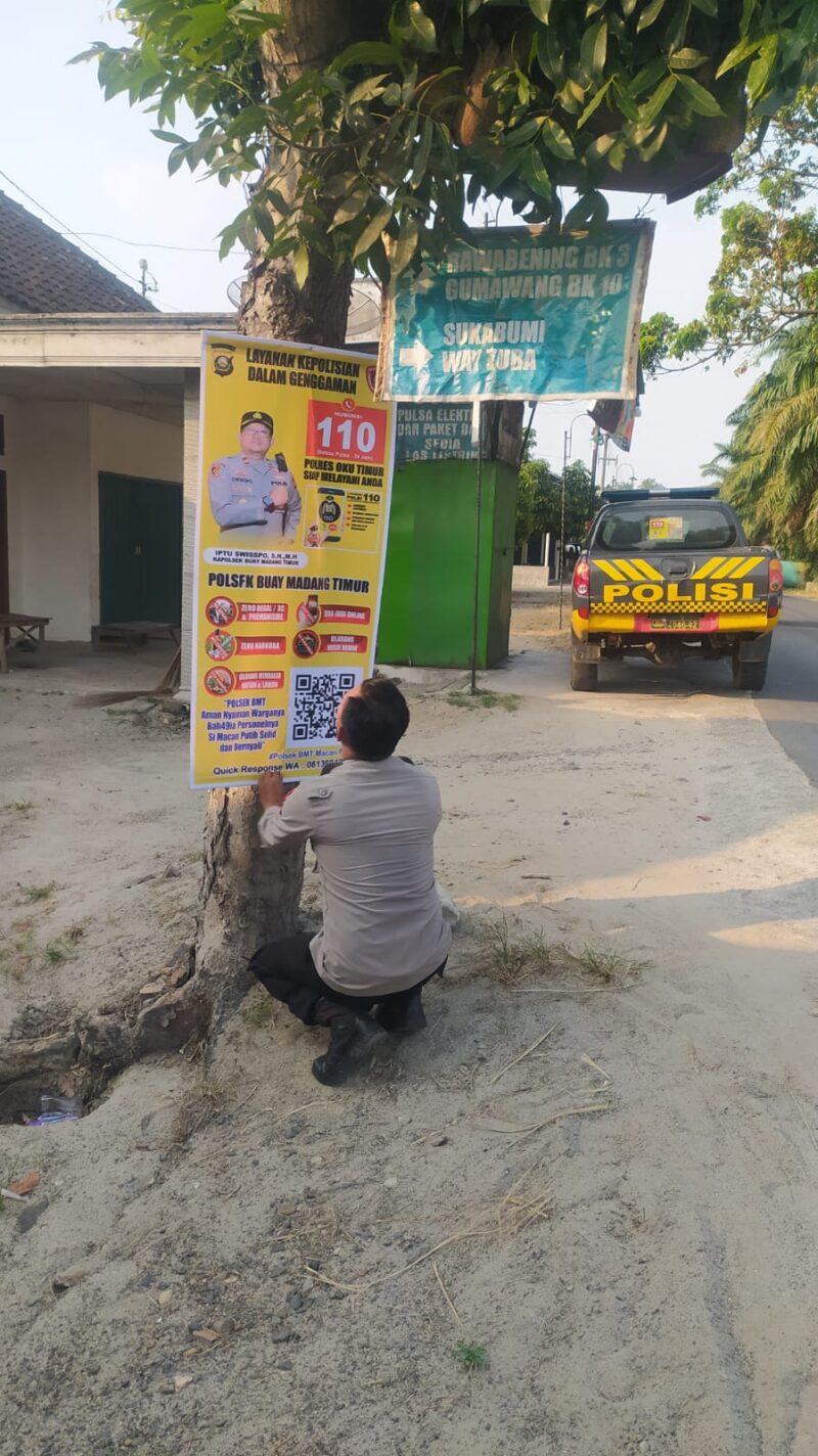 Personel Polsek Buay Madang Timur memasang banner Layanan Kepolisian 110 dan imbauan larangan karhutla di tepi jalan Desa Tanjung Mulya, Kecamatan Buay Madang Timur, OKU Timur. 