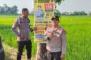 Kapolsek Buay Madang Timur Iptu Swisspo (kanan) bersama Bripka Didi Handoko memasang spanduk Layanan Kepolisian 110 dan imbauan larangan kebakaran hutan dan lahan (Karhutla) di Desa Wonodadi Asri, Kecamatan Buay Madang Timur, Kabupaten OKU Timur. 
