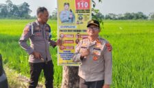 Kapolsek Buay Madang Timur Iptu Swisspo (kanan) bersama Bripka Didi Handoko memasang spanduk Layanan Kepolisian 110 dan imbauan larangan kebakaran hutan dan lahan (Karhutla) di Desa Wonodadi Asri, Kecamatan Buay Madang Timur, Kabupaten OKU Timur. 