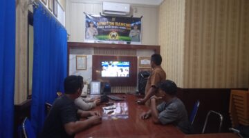 Anggota Polsek Buay Madang Timur bersama masyarakat pencinta sepak bola menyaksikan pertandingan Pesta Bola Dunia 2026 antara Inggris vs Argentina di Mako Polsek Buay Madang Timur, Kabupaten OKU Timur. 