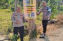 Kapolsek Buay Madang Timur Iptu Swisspo (kiri) bersama personel memperlihatkan spanduk Layanan Kepolisian 110 dan imbauan larangan Karhutla yang dipasang di Desa Sukoharjo, Kecamatan Buay Madang Timur, Kabupaten OKU Timur. 