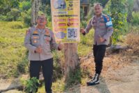 Kapolsek Buay Madang Timur Iptu Swisspo (kiri) bersama personel memperlihatkan spanduk Layanan Kepolisian 110 dan imbauan larangan Karhutla yang dipasang di Desa Sukoharjo, Kecamatan Buay Madang Timur, Kabupaten OKU Timur. 