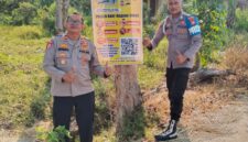Kapolsek Buay Madang Timur Iptu Swisspo (kiri) bersama personel memperlihatkan spanduk Layanan Kepolisian 110 dan imbauan larangan Karhutla yang dipasang di Desa Sukoharjo, Kecamatan Buay Madang Timur, Kabupaten OKU Timur. 