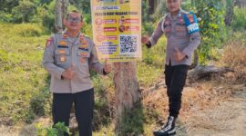 Kapolsek Buay Madang Timur Iptu Swisspo (kiri) bersama personel memperlihatkan spanduk Layanan Kepolisian 110 dan imbauan larangan Karhutla yang dipasang di Desa Sukoharjo, Kecamatan Buay Madang Timur, Kabupaten OKU Timur. 