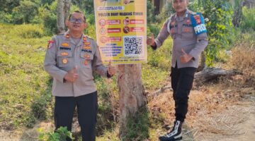 Kapolsek Buay Madang Timur Iptu Swisspo (kiri) bersama personel memperlihatkan spanduk Layanan Kepolisian 110 dan imbauan larangan Karhutla yang dipasang di Desa Sukoharjo, Kecamatan Buay Madang Timur, Kabupaten OKU Timur. 