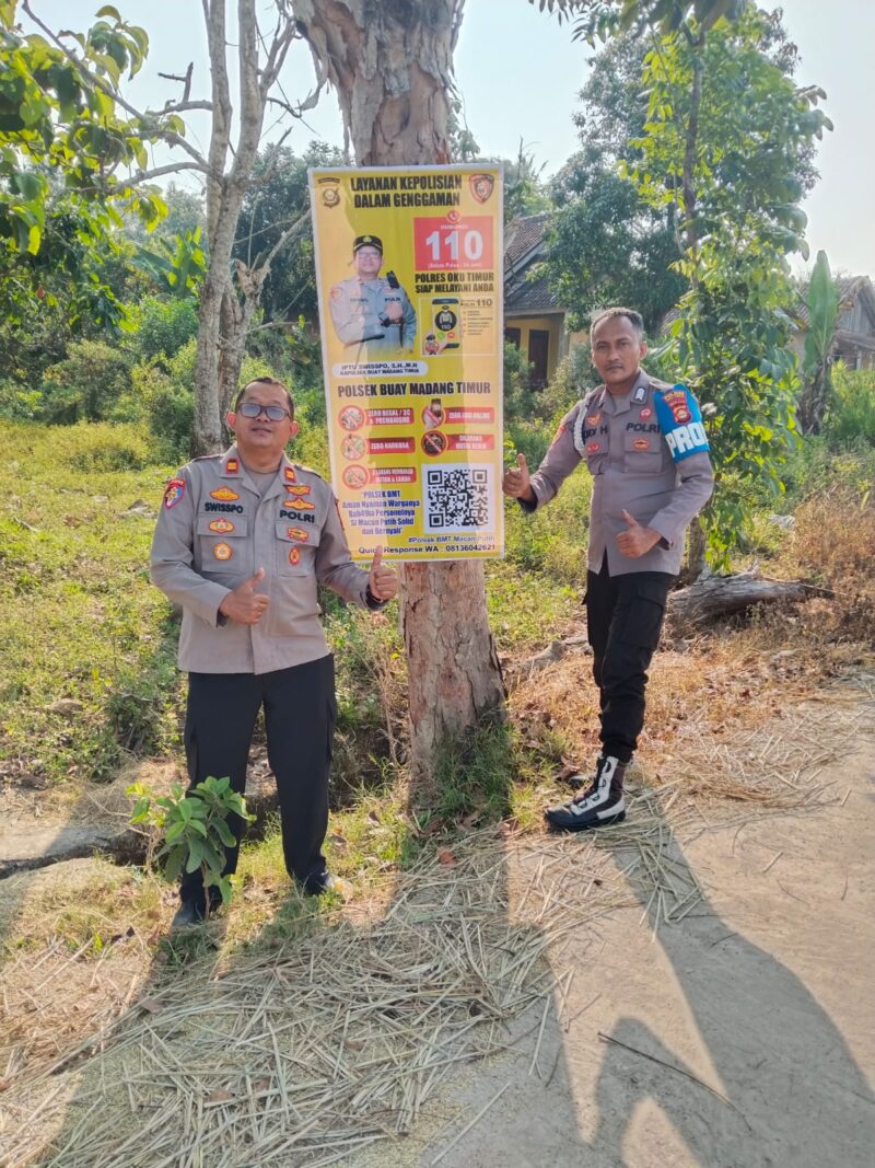 Kapolsek Buay Madang Timur Iptu Swisspo (kiri) bersama personel memperlihatkan spanduk Layanan Kepolisian 110 dan imbauan larangan Karhutla yang dipasang di Desa Sukoharjo, Kecamatan Buay Madang Timur, Kabupaten OKU Timur. 