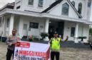 Personel Polsek Buay Madang Timur, Aiptu Mulyono dan Bripka Iswanto, membentangkan spanduk program 