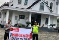 Personel Polsek Buay Madang Timur, Aiptu Mulyono dan Bripka Iswanto, membentangkan spanduk program "Minggu Kasih Polres OKU Timur" saat melakukan pengamanan ibadah di depan Gereja Trinitas Bangun Sari, Kecamatan Buay Madang Timur, OKU Timur. 