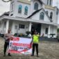 Personel Polsek Buay Madang Timur, Aiptu Mulyono dan Bripka Iswanto, membentangkan spanduk program 