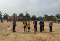 Personel Polsek BMT melakukan pengamanan melekat di tengah Lapangan Desa Karang Tengah saat berlangsungnya hari kedua Turnamen Sepak Bola Tingkat SD #BMT Cup 2026 di Kabupaten OKU Timur. 