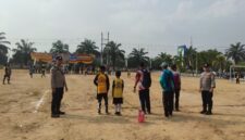 Personel Polsek BMT melakukan pengamanan melekat di tengah Lapangan Desa Karang Tengah saat berlangsungnya hari kedua Turnamen Sepak Bola Tingkat SD #BMT Cup 2026 di Kabupaten OKU Timur.