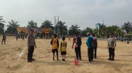 Personel Polsek BMT melakukan pengamanan melekat di tengah Lapangan Desa Karang Tengah saat berlangsungnya hari kedua Turnamen Sepak Bola Tingkat SD #BMT Cup 2026 di Kabupaten OKU Timur. 