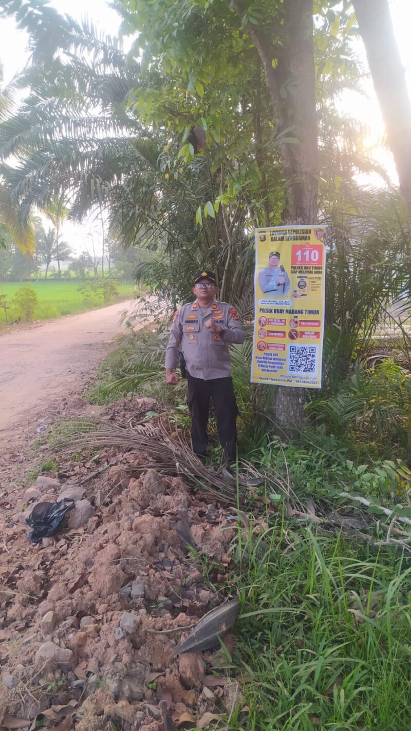 Kapolsek Buay Madang Timur Iptu Swisspo, menunjukkan spanduk Layanan Kepolisian 110 yang dipasang di kawasan Desa Sumedang Sari, Kecamatan Buay Madang Timur, Kabupaten OKU Timur. 