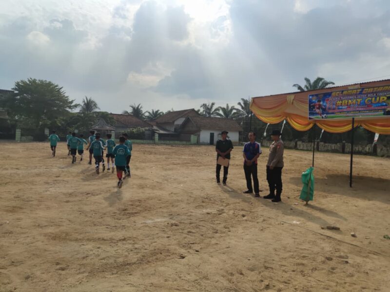 Personel Polsek Buay Madang Timur memantau situasi lapangan saat mendampingi pelaksanaan hari ketiga Turnamen Sepak Bola Anak SD #BMT Cup 2026 di Desa Karang Tengah, OKU Timur. 