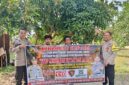 Personel Polsek Buay Madang Timur, Polres OKU Timur, membentangkan spanduk himbauan 