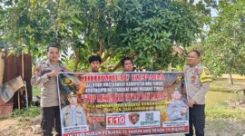 Personel Polsek Buay Madang Timur, Polres OKU Timur, membentangkan spanduk himbauan 