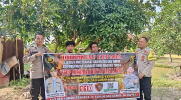 Personel Polsek Buay Madang Timur, Polres OKU Timur, membentangkan spanduk himbauan 