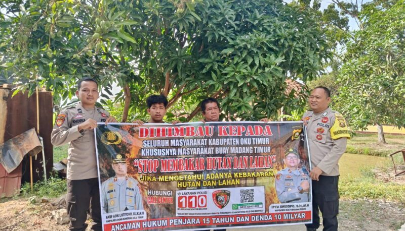 Personel Polsek Buay Madang Timur, Polres OKU Timur, membentangkan spanduk himbauan 