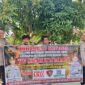 Personel Polsek Buay Madang Timur, Polres OKU Timur, membentangkan spanduk himbauan 