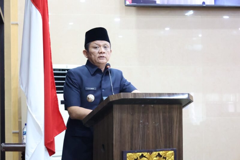 Bupati OKU Timur Lanosin, menyampaikan jawaban pemerintah terhadap pemandangan umum fraksi-fraksi DPRD atas Raperda Pertanggungjawaban Pelaksanaan APBD TA 2025 di Ruang Rapat Paripurna DPRD OKU Timur. 