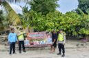 Personel Polsek Buay Madang Timur bersama warga membentangkan spanduk imbauan 