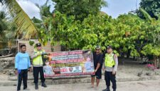 Personel Polsek Buay Madang Timur bersama warga membentangkan spanduk imbauan 