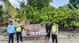 Personel Polsek Buay Madang Timur bersama warga membentangkan spanduk imbauan 